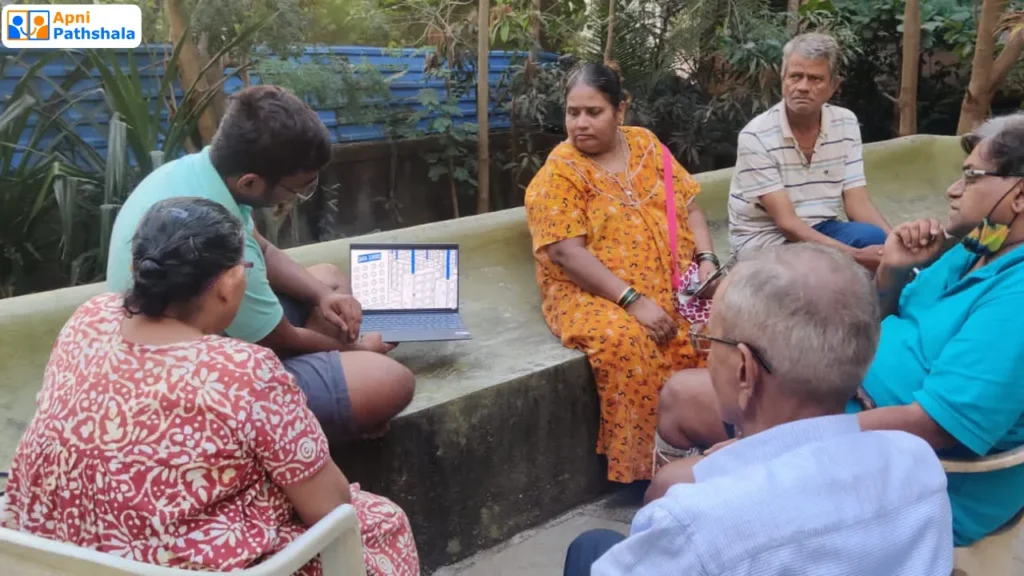 A student from Apni Pathshala teaching digital skills to senior community members using a laptop during a community learning session.A Self-Directed Learners teaching Parents.