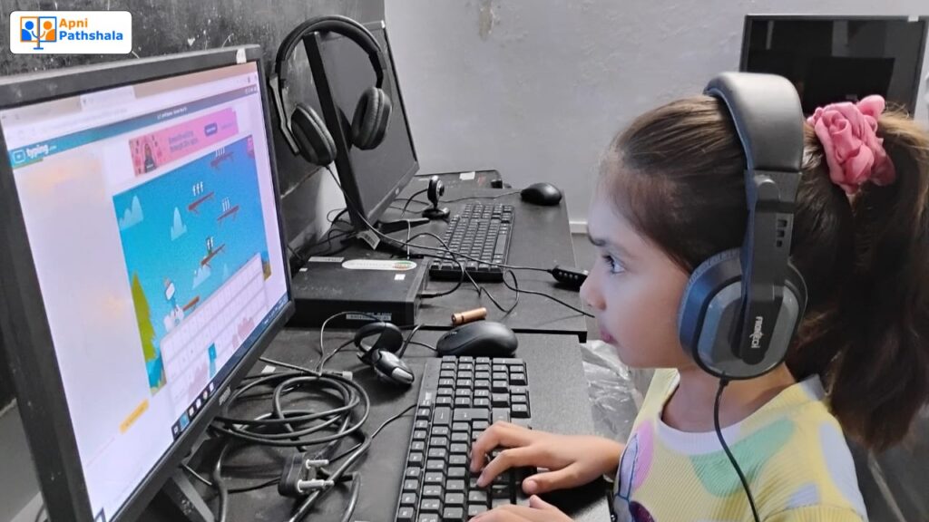 A young girl learning digital skills on an Apna PC inside an Apni Pathshala Learning POD, wearing headphones and practicing typing on an educational game.